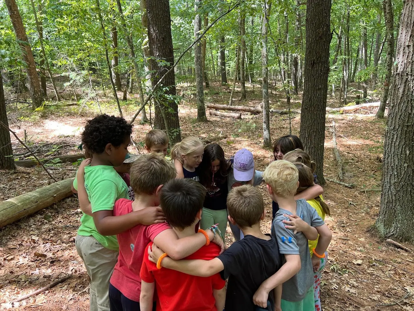 Image of children huddled together amidst the beauty of nature during a nature school program.